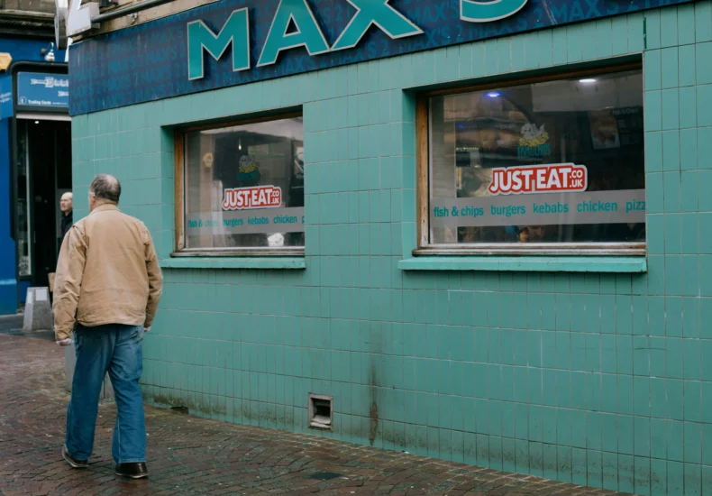 Man walking past shops in an urban street setting in Inverness, Scotland, captured on a cool day.