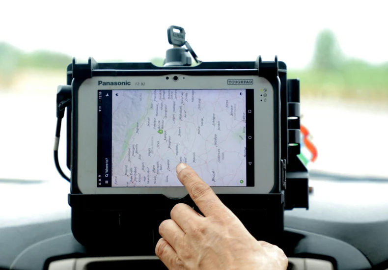 Close-up of hand interacting with GPS navigation on a car-mounted tablet screen, showcasing modern technology.