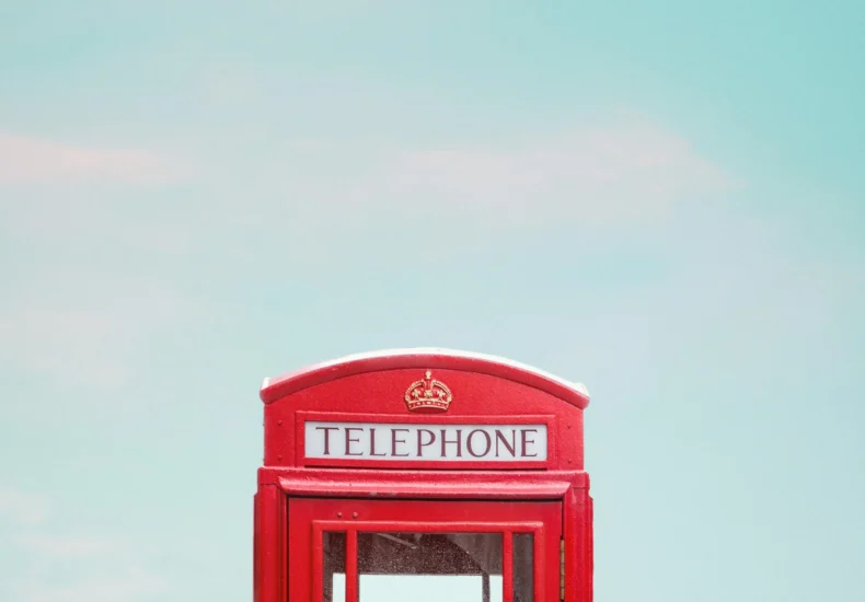 Minimalist photo of a red telephone booth in London with a clear blue sky.