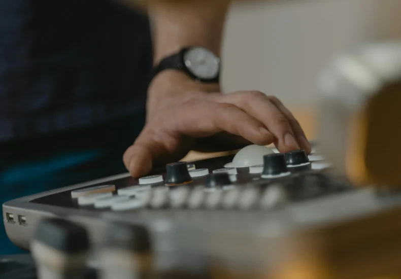 A healthcare professional operates medical equipment indoors, focusing on control panel details.