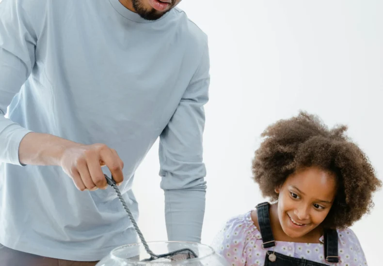 Father and daughter enjoying time together while cleaning a fishbowl. Perfect family moment.