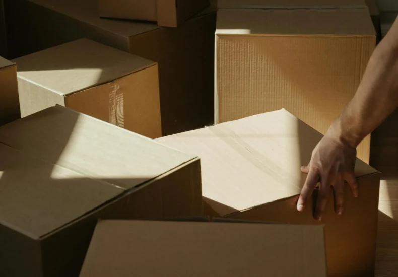 Sunlit room with person moving cardboard boxes, symbolizing relocation and new beginnings.