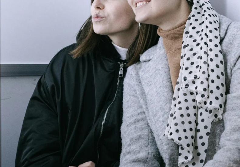 Two women enjoy a candid moment together in a photo booth, showcasing their friendship and support.
