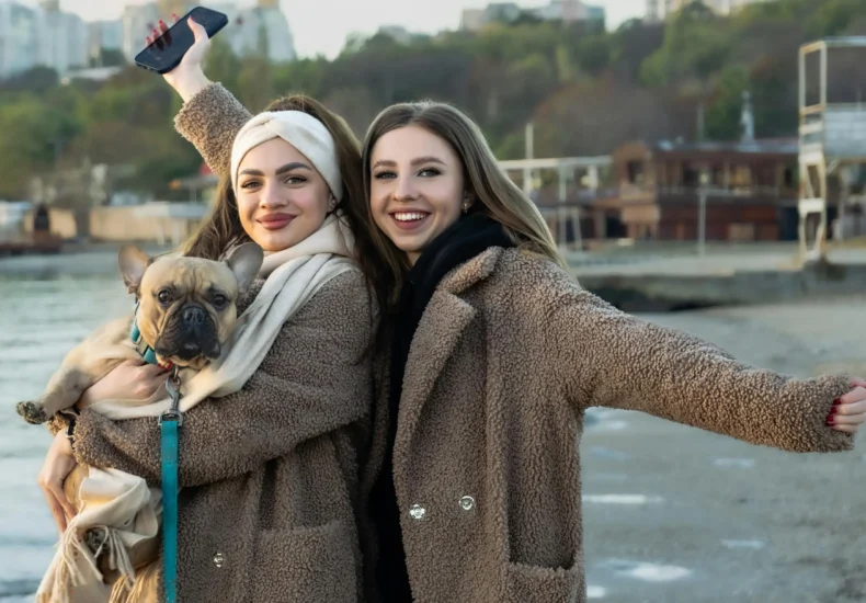 Two women smiling on a winter beach with their dog in Odessa, Ukraine.