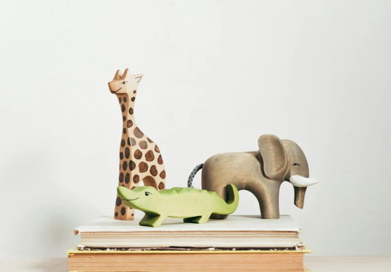 Charming display of wooden animal toys on stacked books, perfect for children's decor.
