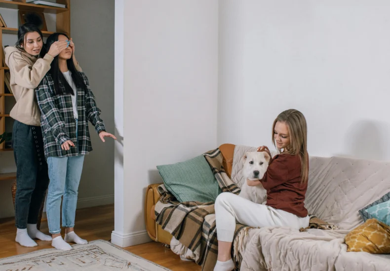 Three women share a joyful moment with a surprise gift—a cute dog, creating a heartwarming scene.