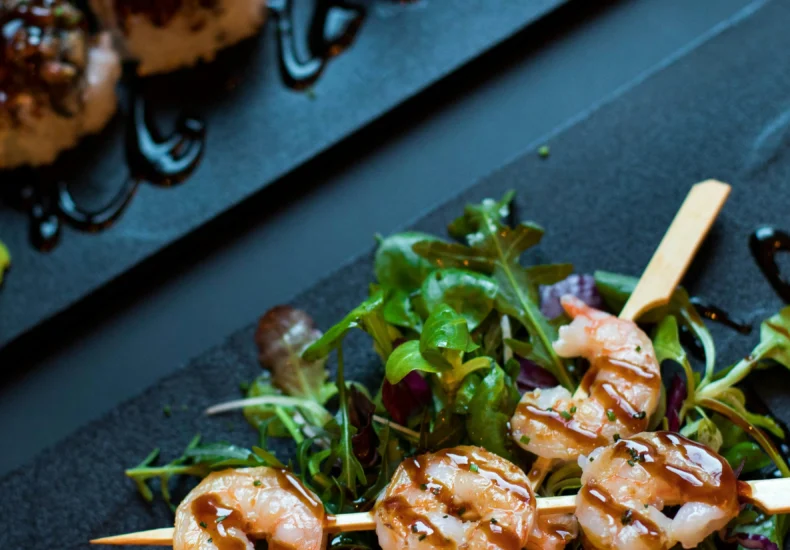 Delicious grilled shrimp skewers served with mixed greens and balsamic glaze, perfect for a gourmet dining experience.