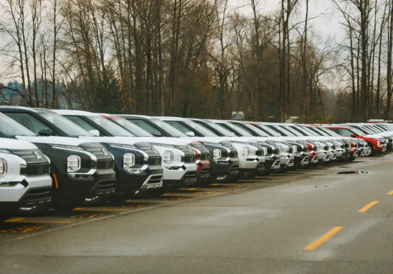 A line of brand new SUVs in an outdoor parking lot during a cloudy day.