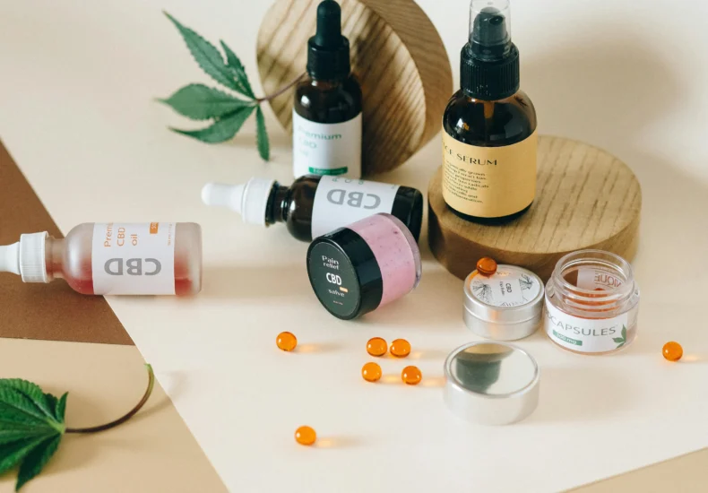 A collection of CBD products including oils and capsules on a neutral background with hemp leaves.