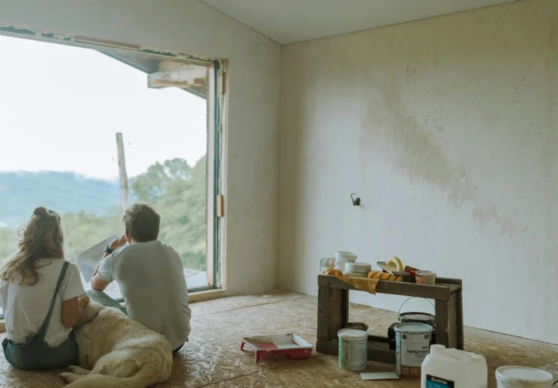A couple with their dog resting in a partially renovated room, planning the renovation.