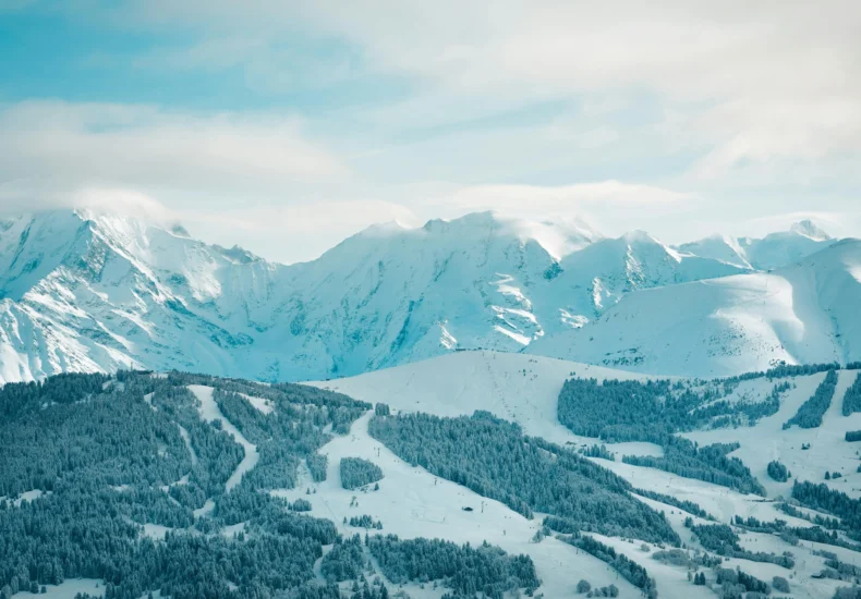 A serene winter landscape showcasing snow-covered mountains and forests in Megève, France.