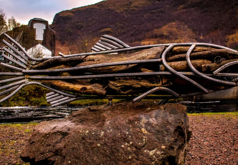 An iron and wood fish sculpture outdoors in scenic Highland, Scotland.