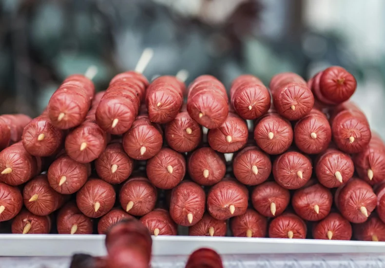 Close-up of stacked uncooked hotdogs on skewers ready for grilling, ideal for summer barbecues.