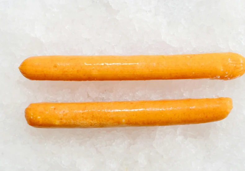 A detailed view of two fresh sausages placed on a bed of ice, perfect for food presentation.